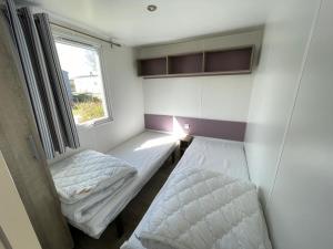 a small room with two beds and a window at Low Budget - Luxe 4 persoons chalet met TV aan het Lauwersmeer in Lauwersoog