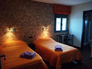 two beds in a room with orange sheets at Pensión Matarraña in Fayón
