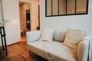 eine weiße Couch mit zwei Kissen darauf in einem Wohnzimmer in der Unterkunft Appartement cosy proche centre, marché de Noël in Metz