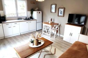 a kitchen with white cabinets and a table and a refrigerator at Logement lumineux bord de forêt in Aubenas
