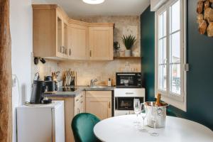 a kitchen with a white table and green walls at Gatsby - Élégant, Central, Fibre, Tv 4K, Netflix, Literie Confortable in La Rochelle +14 photos