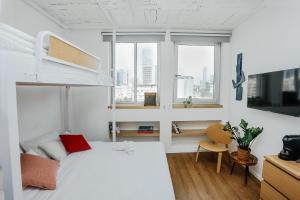 a bedroom with a bed and a desk and windows at Domus Metro Hotel in Tel Aviv