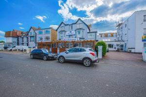 two cars parked in a parking lot in front of a building at Pier Hotel Clacton on Sea By OYO in Clacton-on-Sea
