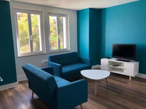 a living room with blue walls and a table and chairs at Les Coteaux in Gérardmer