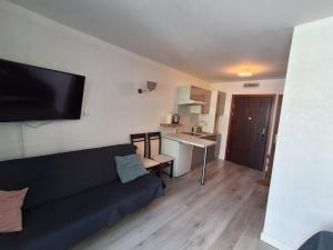 a living room with a black couch and a kitchen at Apartament Blisko Morza 59 in Kołobrzeg