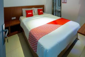 a bedroom with a large bed with red pillows at Hotel O Point Inn in Jakarta