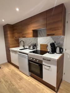 a kitchen with white appliances and wooden cabinets at Écrin paisible in Vergèze