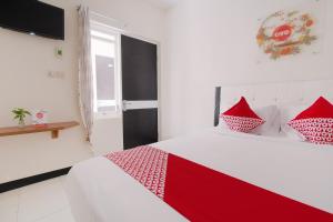 a white bedroom with red pillows on a bed at Hotel O Cozy Residence Syariah in Malang