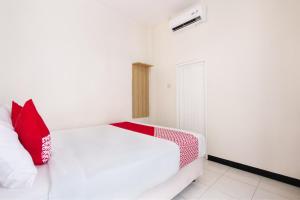 a bedroom with a white bed with red pillows at Hotel O Cozy Residence Syariah in Malang
