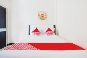 a bedroom with a white bed with red pillows at Hotel O Cozy Residence Syariah in Malang