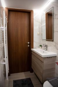 a bathroom with a sink and a wooden door at Reggina Apartment in Arta +25 photos