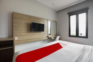a bedroom with a bed with a television on the wall at Collection O Bekasi Timur Near Gedung Juang Formerly Regia Tambun in Bekasi