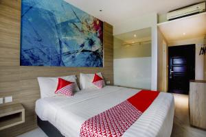 a bedroom with a large bed with a painting on the wall at Collection O Bekasi Timur Near Gedung Juang Formerly Regia Tambun in Bekasi