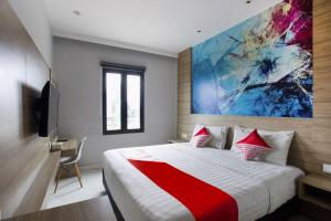 a bedroom with a large bed with a painting on the wall at Collection O Bekasi Timur Near Gedung Juang Formerly Regia Tambun in Bekasi