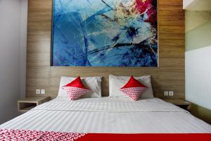 a bedroom with a bed with red pillows and a painting at Collection O Bekasi Timur Near Gedung Juang Formerly Regia Tambun in Bekasi +18 photos