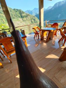 una terraza de madera con mesas y sillas y vistas a las montañas en Batad Pension and Restaurant Native House, en Banaue