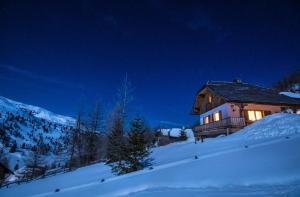 a house on a snowy hill at night in the snow at AUSZEIT Almchalet in Ramingstein