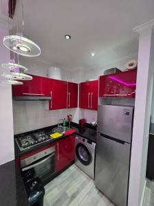 a kitchen with red cabinets and a washing machine at Cabo Apparte Piscine & Panoramique View K17 in Cabo Negro