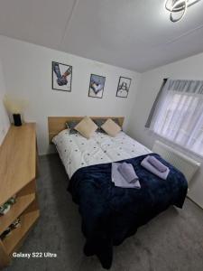 a bedroom with a large bed with purple towels on it at Forest Valley Holiday Home in Ballantrae