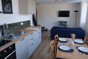 a kitchen with a table and a blue couch at Les Hortensias in Lanvénec +14 photos