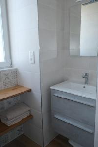 a white bathroom with a sink and a mirror at Les Hortensias in Lanvénec