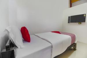 een kleine slaapkamer met een wit bed met rode kussens bij Restu Inn in Lampung