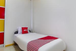 een slaapkamer met een wit bed en een rood kussen bij Restu Inn in Lampung