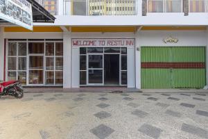 a building with a green door and a motorcycle parked outside at Hotel O Restu Inn in Lampung +34 photos