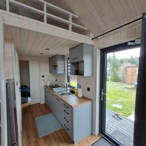a kitchen in a tiny house with a large window at Brzozowe Ostrowie in Kozłowo
