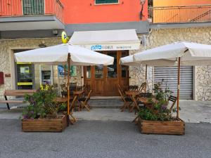 two umbrellas and tables and chairs outside a restaurant at Pippo a Vernazza Rooms in Vernazza