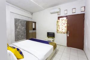 a bedroom with a bed and a television in it at Hotel O near Metropolitan Mall formerly Sakura Home Stay in Kaum