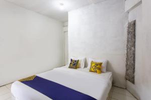 a white room with a bed with yellow and blue pillows at Hotel O near Metropolitan Mall formerly Sakura Home Stay in Kaum