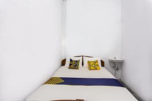 a bedroom with a bed with yellow and blue pillows at Hotel O near Metropolitan Mall formerly Sakura Home Stay in Kaum +23 photos
