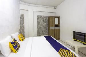 a bedroom with a bed with yellow and blue pillows at Hotel O near Metropolitan Mall formerly Sakura Home Stay in Kaum
