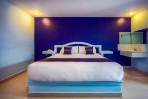a bedroom with a large bed with a blue wall at Capital O Hotel Diro, Monterrey in Monterrey