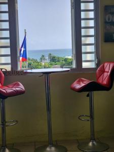 a table with two chairs and a window with a flag at Tamara Guest House in Luquillo