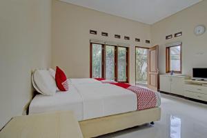 a bedroom with a large white bed with red pillows at OYO 89997 Hotel Bumi Kedaton Waterpark in Bandar Lampung +30 photos