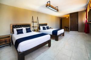 a bedroom with two beds with blue and white pillows at Capital O Hotel Diez in Celaya