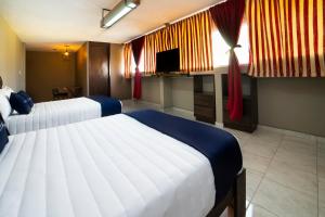 a hotel room with two beds and a television at Capital O Hotel Diez in Celaya +28 photos