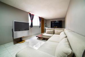 a living room with a couch and a flat screen tv at Capital O Hotel Diez in Celaya