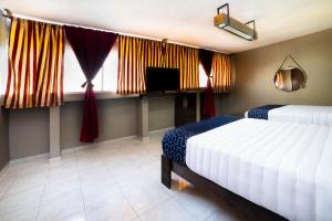 a bedroom with two beds and a tv and windows at Capital O Hotel Diez in Celaya