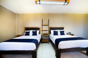 two beds sitting next to each other in a room at Capital O Hotel Diez in Celaya