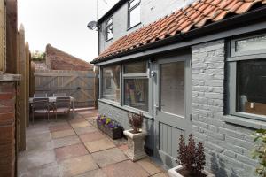 a patio with a house with a window and a table at No33 HILLVIEW LODGE BOUTIQUE COTTAGE in Brancaster +6 photos