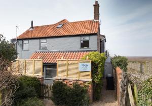 a house with an orange roof and a fence at No33 HILLVIEW LODGE BOUTIQUE COTTAGE in Brancaster