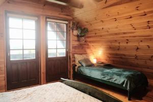 a log cabin bedroom with a bed and a door at Dom Zielarki na Kaszubach - widok na jezioro, sauna, balia in Żuromino