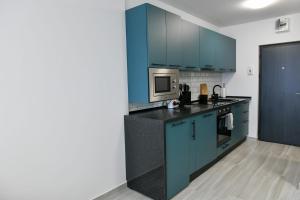 a kitchen with blue cabinets and a black counter top at SiaNest in Piatra Neamţ