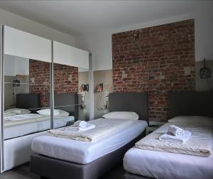 a room with three beds and a brick wall at Haus 15 Apartments Monteurwohnungen in Bielefeld
