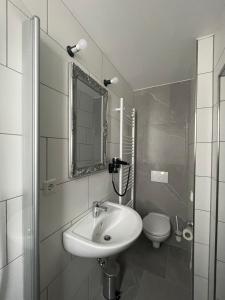 a white bathroom with a sink and a toilet at Haus 15 Apartments Monteurwohnungen in Bielefeld