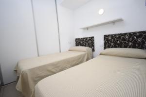 due letti in una stanza con pareti bianche di CABALLOS 2D - ESTUDIO - Fincas Arena a Benidorm