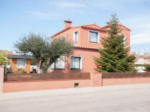 una casa rosa con un árbol delante en Belvilla by OYO Marinada, en Sant Pere Pescador
